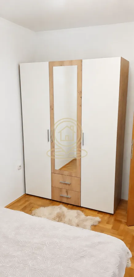 Spavaća soba sa velikim garderoberom sa ogledalom i drvenim podom.
