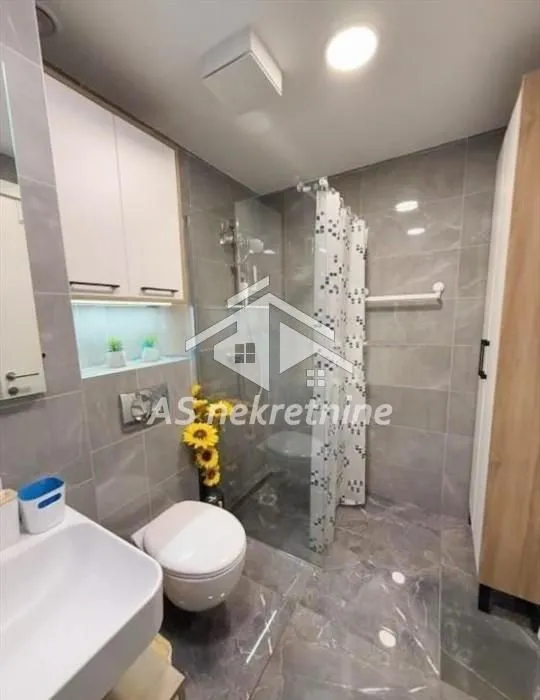 Moderno kupatilo sa tuš kabinom, umivaonikom i ugradnom wc šoljom.
