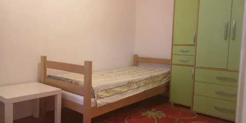 Jednostavna spavaća soba sa jednim krevetom i zelenim ormarom. - image 10