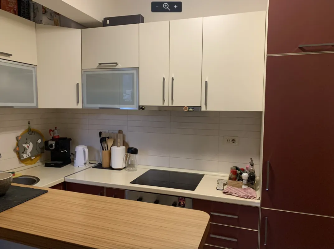 Compact kitchen with white wall cabinets and a built-in cooktop.