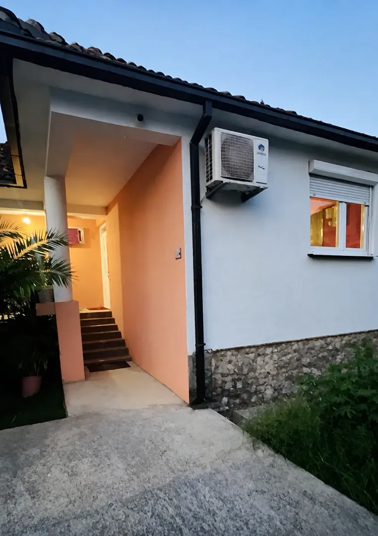 Pogled na spoljašnjost kuće sa ulaznim stepeništem i fasadom.
