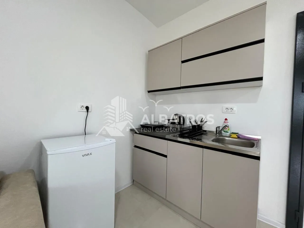 Small kitchen with a sink, cabinetry, and a small refrigerator.