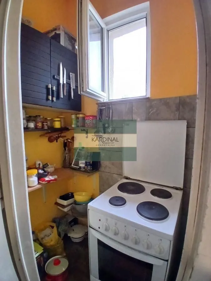 Manja kuhinja sa šporetom i otvorenim policama.