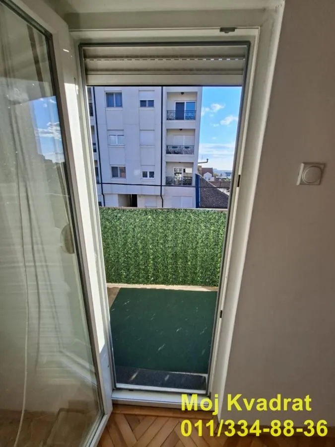 View through the balcony door to the terrace and surrounding buildings.
