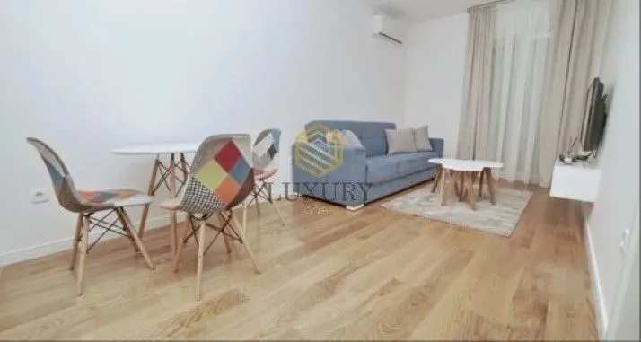 Dnevni boravak sa garniturom, trpezarijskim stolom i drvenim podom.