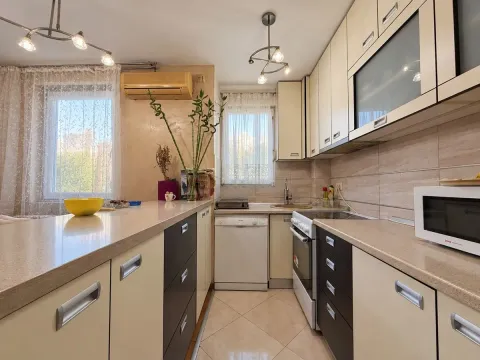 Kuhinja sa elementima u krem i tamnim tonovima i šankom. - image 11