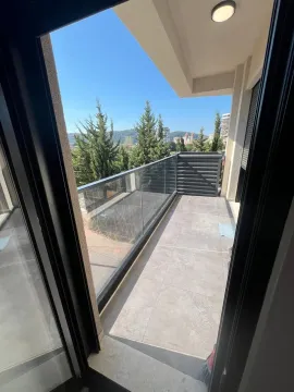 Spacious balcony with a glass railing and a view of greenery and surroundings. - image 4