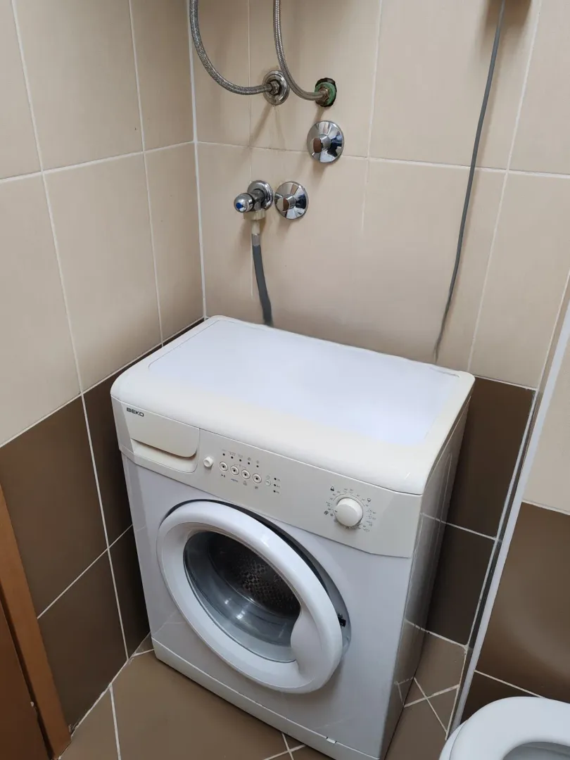 Bathroom with a washing machine and ceramic tiles.