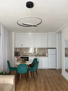 Modern white kitchen with a dining table and green chairs. - image 4