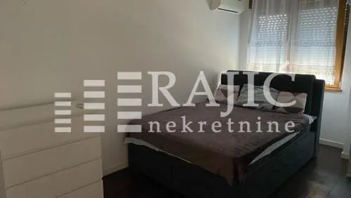 Nameštena spavaća soba sa bračnim krevetom i komodom.