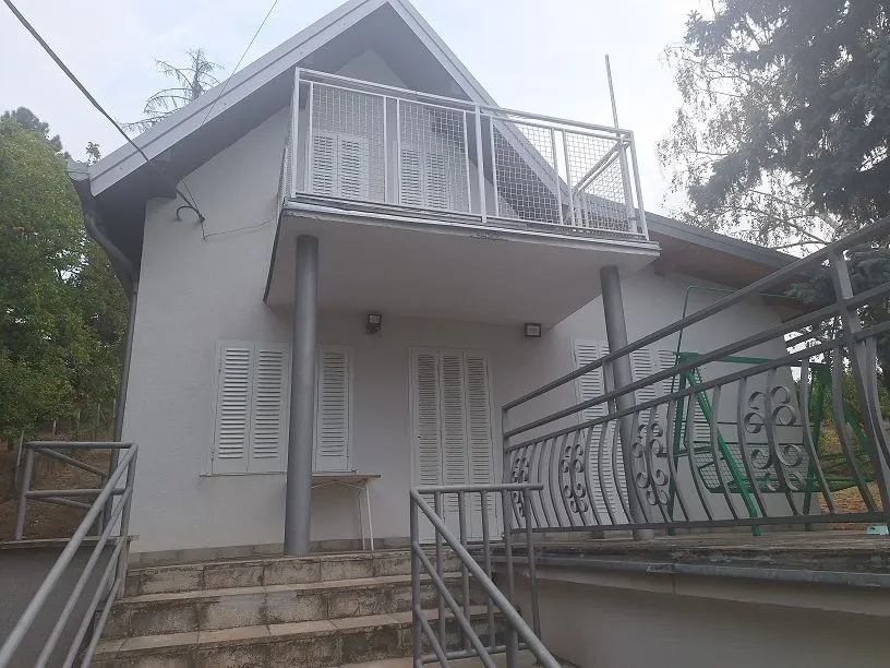 Spoljašnji izgled kuće sa stepeništem i balkonom na spratu.