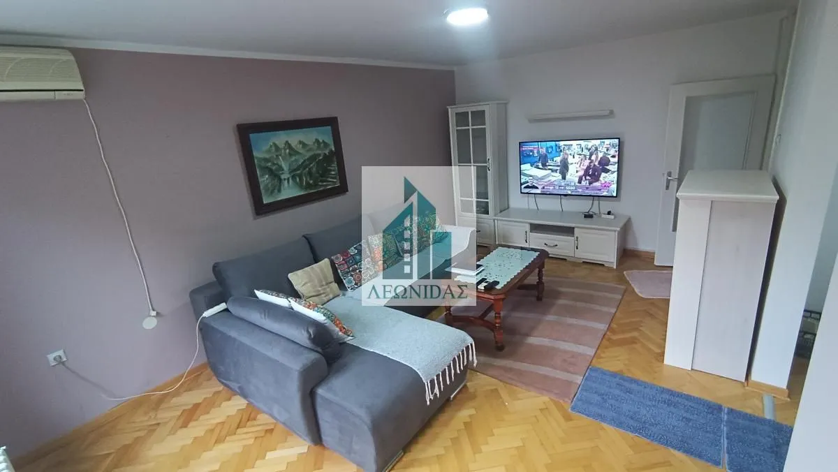 Living room with a corner sofa, television, and wooden flooring.