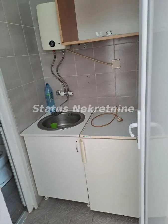 Smaller kitchen with a sink, water heater, and cabinets.