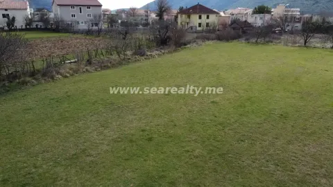 Pogled na zeleni plac sa kućama u pozadini. - image 2