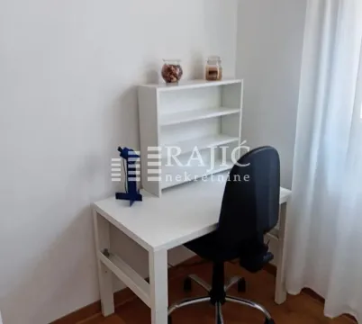 A desk with a chair and a white shelf in a room. - image 8
