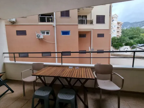 Covered balcony space with a table and chairs overlooking surrounding buildings. - image 7