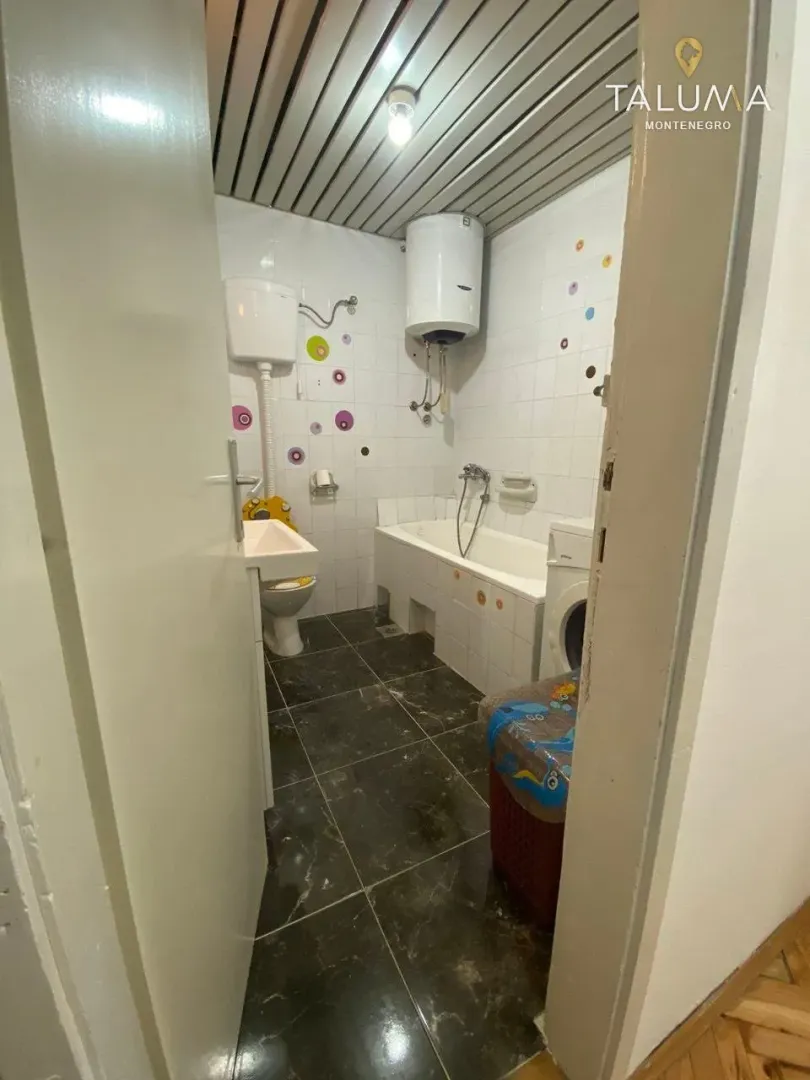 View of the bathroom with a bathtub, sink, and water heater.