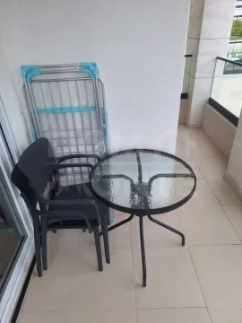 Smaller terrace with a glass table, black chairs, and a folded drying rack. - image 13