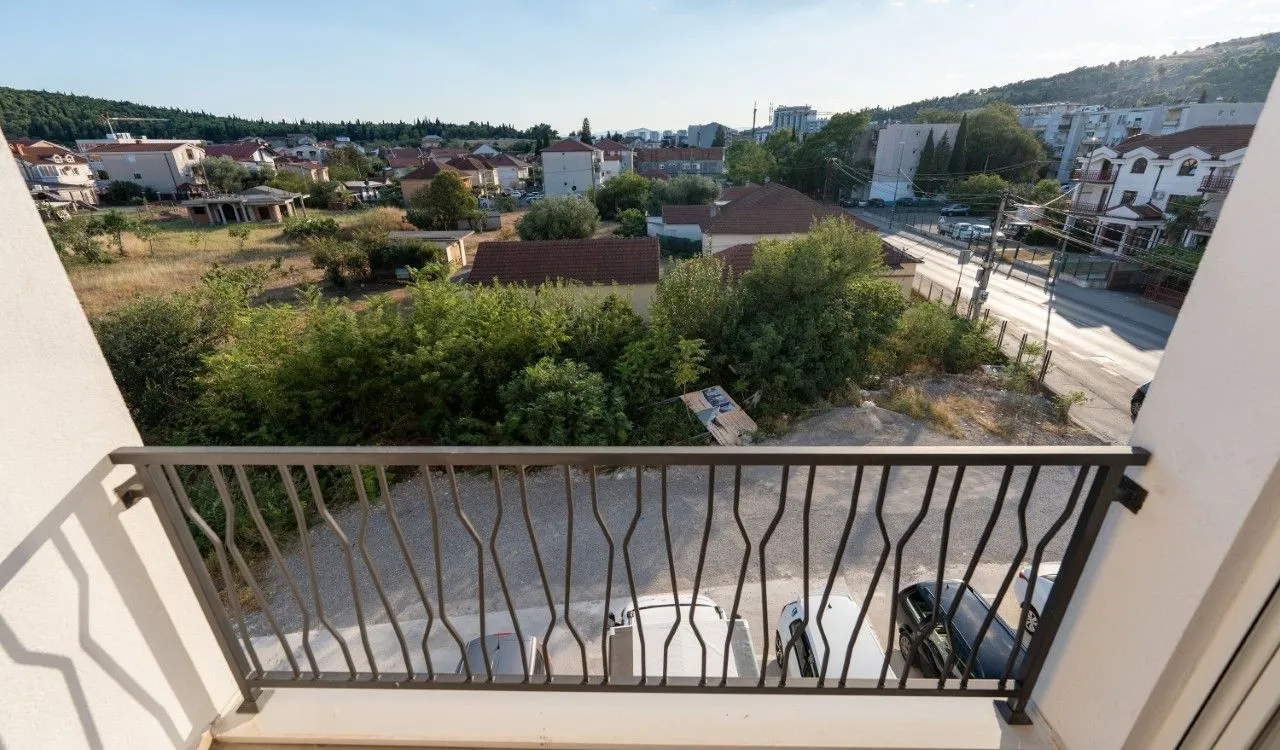 Pogled sa balkona na okolno naselje i zelenilo.