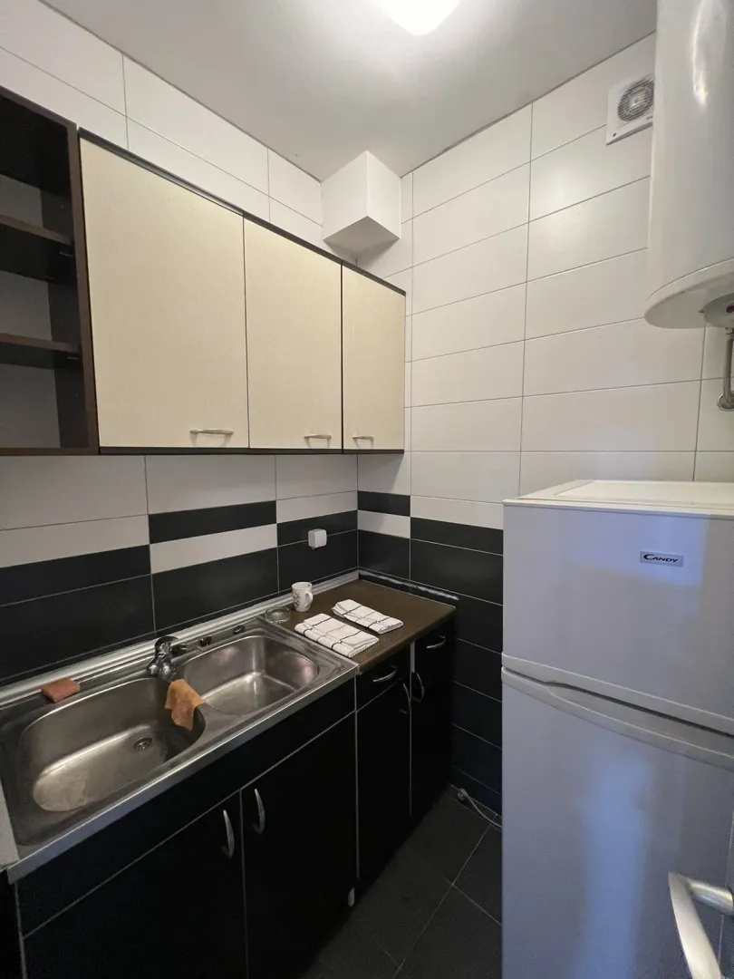 Small kitchen with black and white tiles, a sink, and a refrigerator.