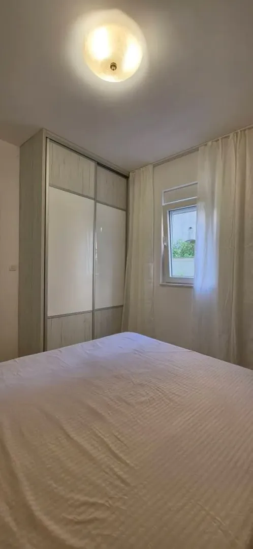 Spavaća soba sa bračnim krevetom, garderoberom i prozorom.