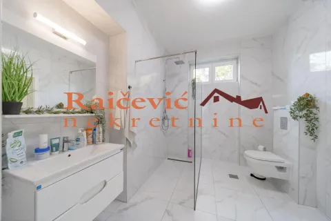 Modern bathroom with white marble tiles, a walk-in shower with glass partition, and a wall-hung toilet. - image 4