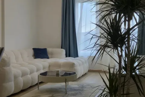 Living room with a white sectional sofa, coffee table, and a houseplant. - image 3
