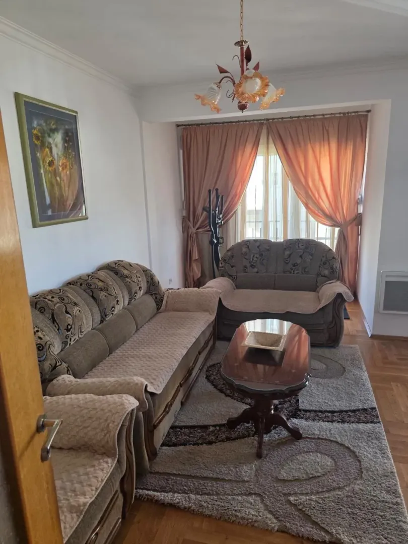 Living room with a seating set, coffee table, and a window with curtains.