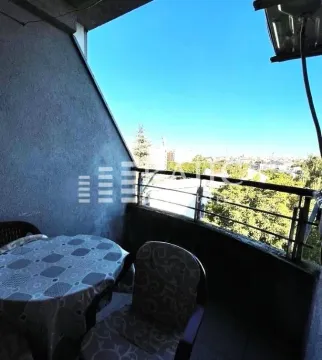 Covered terrace with a table, chairs, and a city view. - image 12