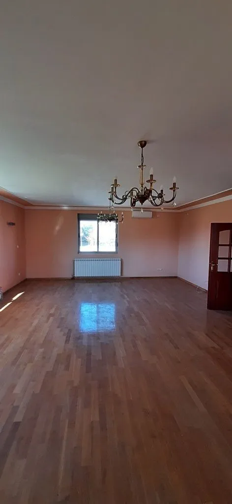 Empty spacious living room with wooden flooring and chandeliers.
