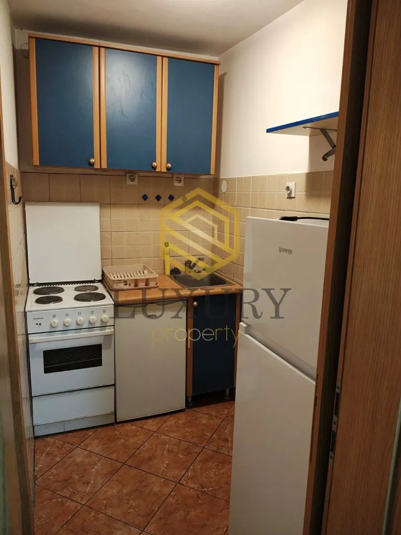 Smaller kitchen with blue and wood-colored elements, stove, and refrigerator.