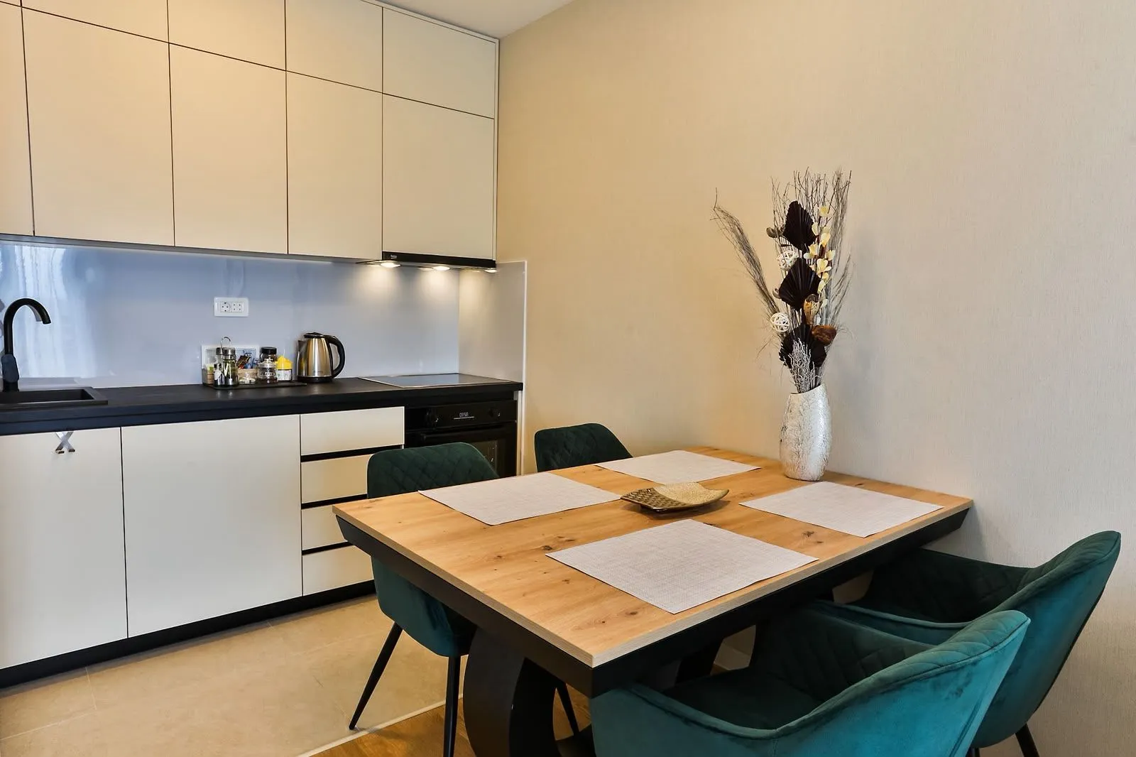 Modern kitchen with a dining table and green chairs.