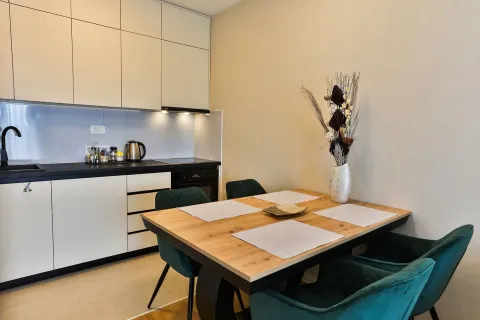 Modern kitchen with a dining table and green chairs. - image 3