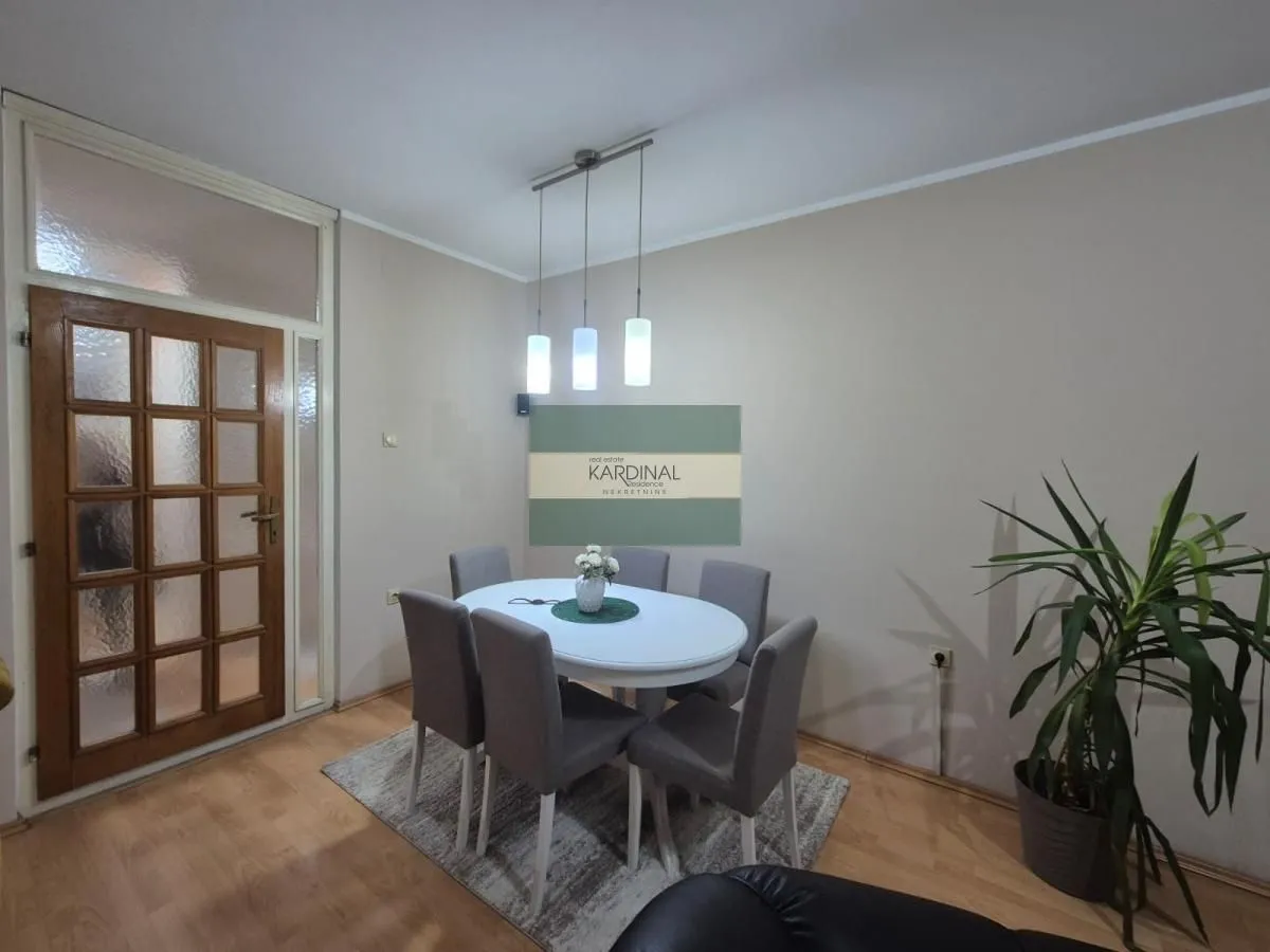 Trpezarija sa stolom, stolicama i lusterom.