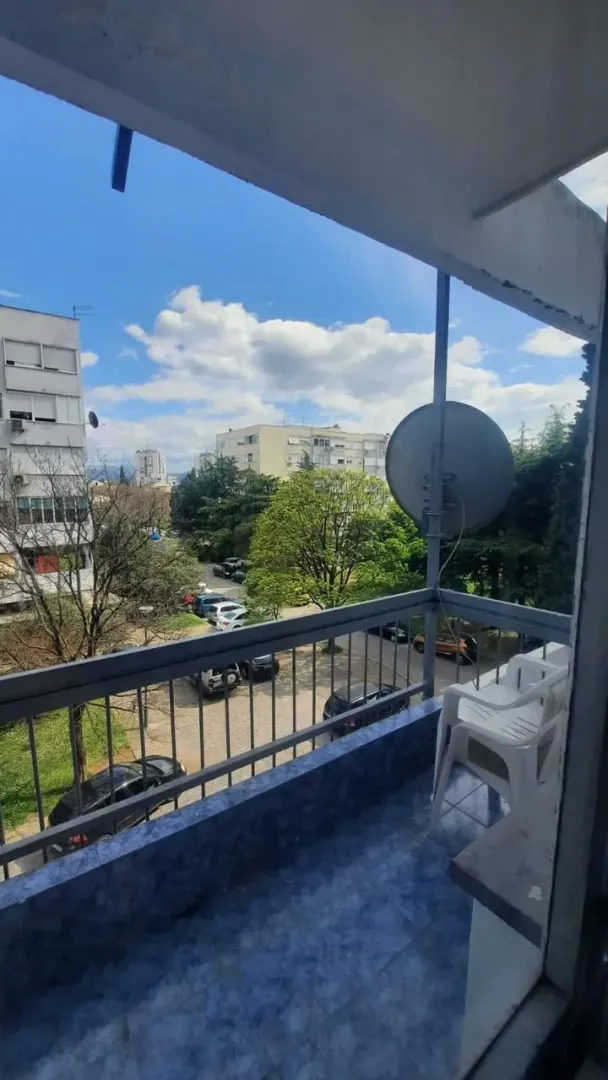Small balcony with tiled flooring and a view of the urban neighborhood and parking area.