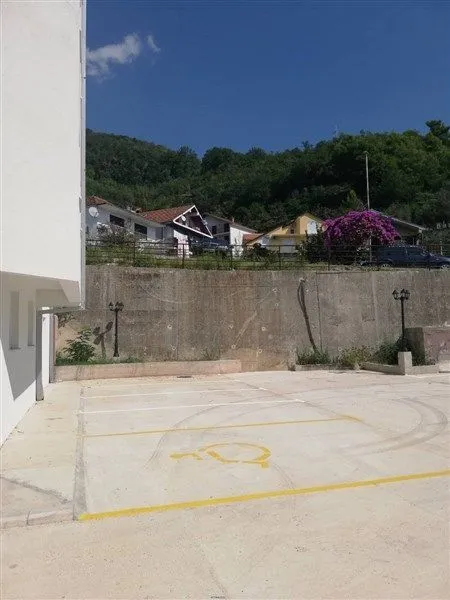 Parking prostor ispred zgrade sa označenim parking mjestima.