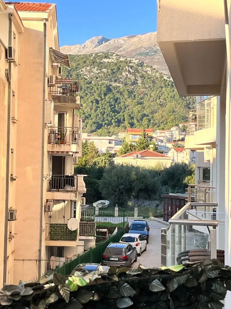 Pogled sa terase na okolne zgrade, ulicu i planine u pozadini.
