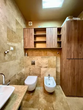 Modern bathroom with a toilet, bidet, washbasin, and wooden cabinets. - image 10