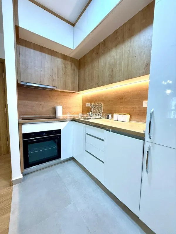 Modern kitchen with white cabinets and wooden details.