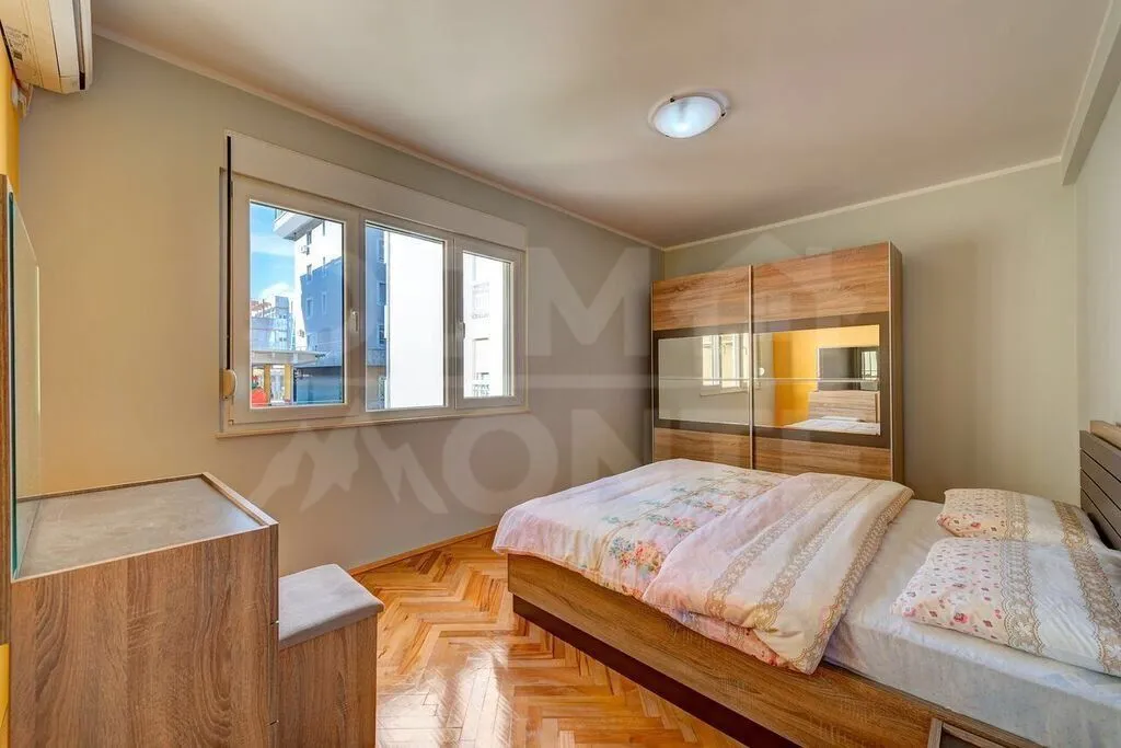 Furnished bedroom with a double bed, wardrobe, and parquet flooring.