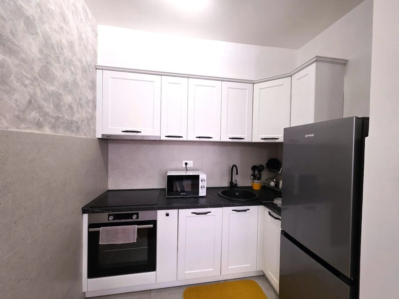 Small kitchen with white cabinets and a black countertop.
