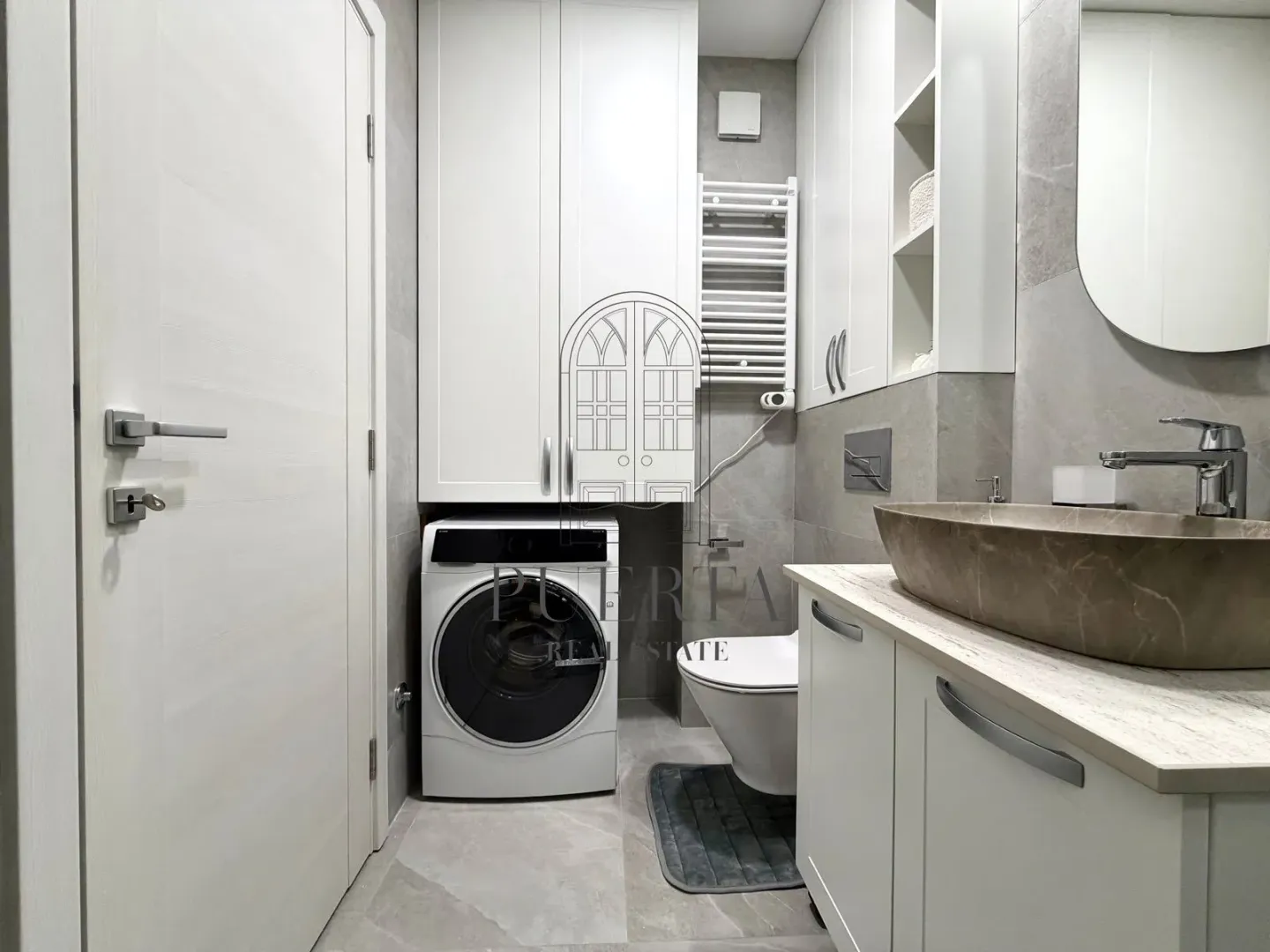 Modernly equipped bathroom with a washing machine and white furniture.