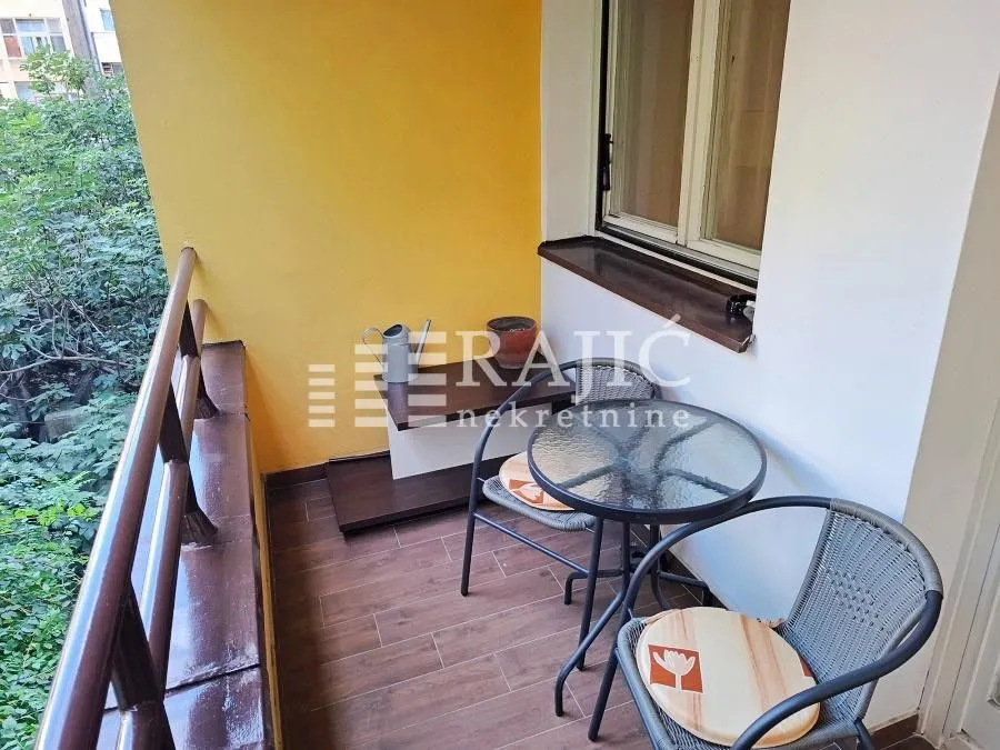 Smaller covered terrace furnished with seating furniture.