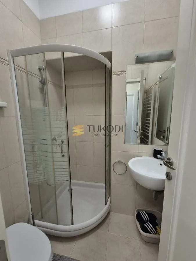 Kupatilo sa tuš kabinom, umivaonikom i ogledalom.