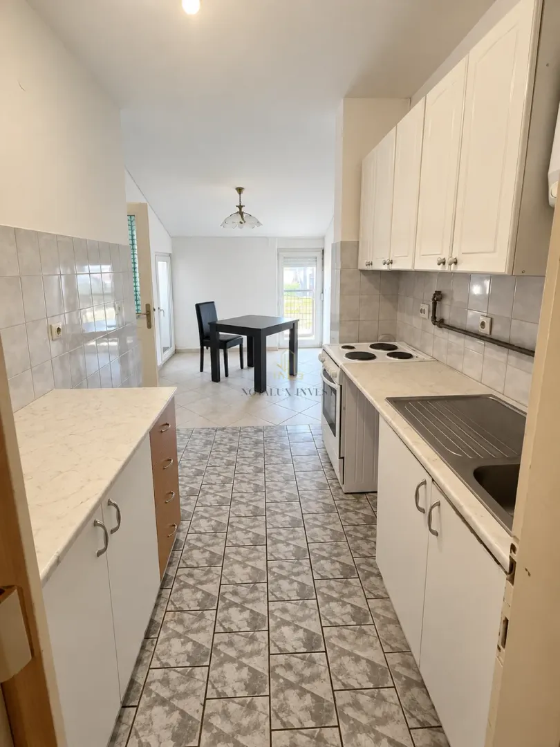 Smaller kitchen with white cabinetry and a dining area beyond.