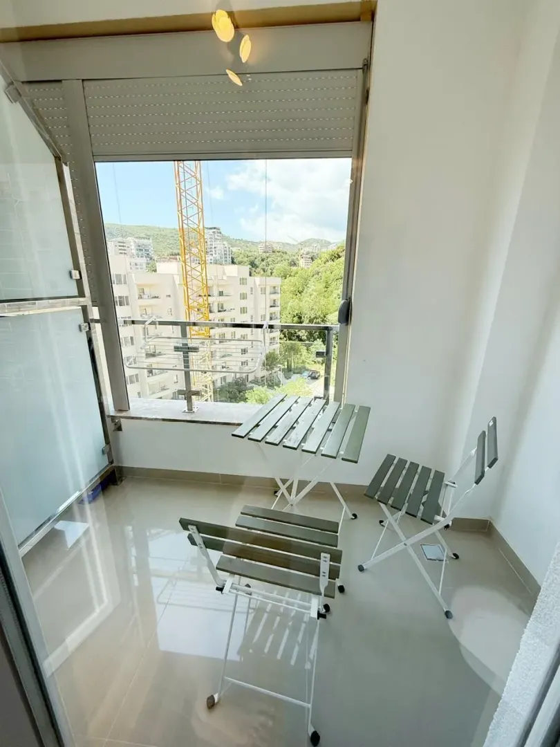 Small furnished balcony with a table and chairs and a view of surrounding buildings.