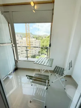 Small furnished balcony with a table and chairs and a view of surrounding buildings. - image 11