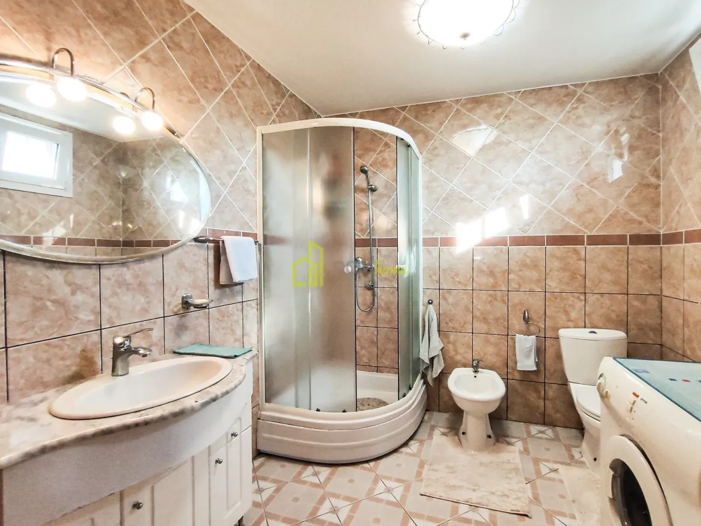 Bathroom equipped with a shower cabin, washbasin, toilet, bidet, and washing machine.