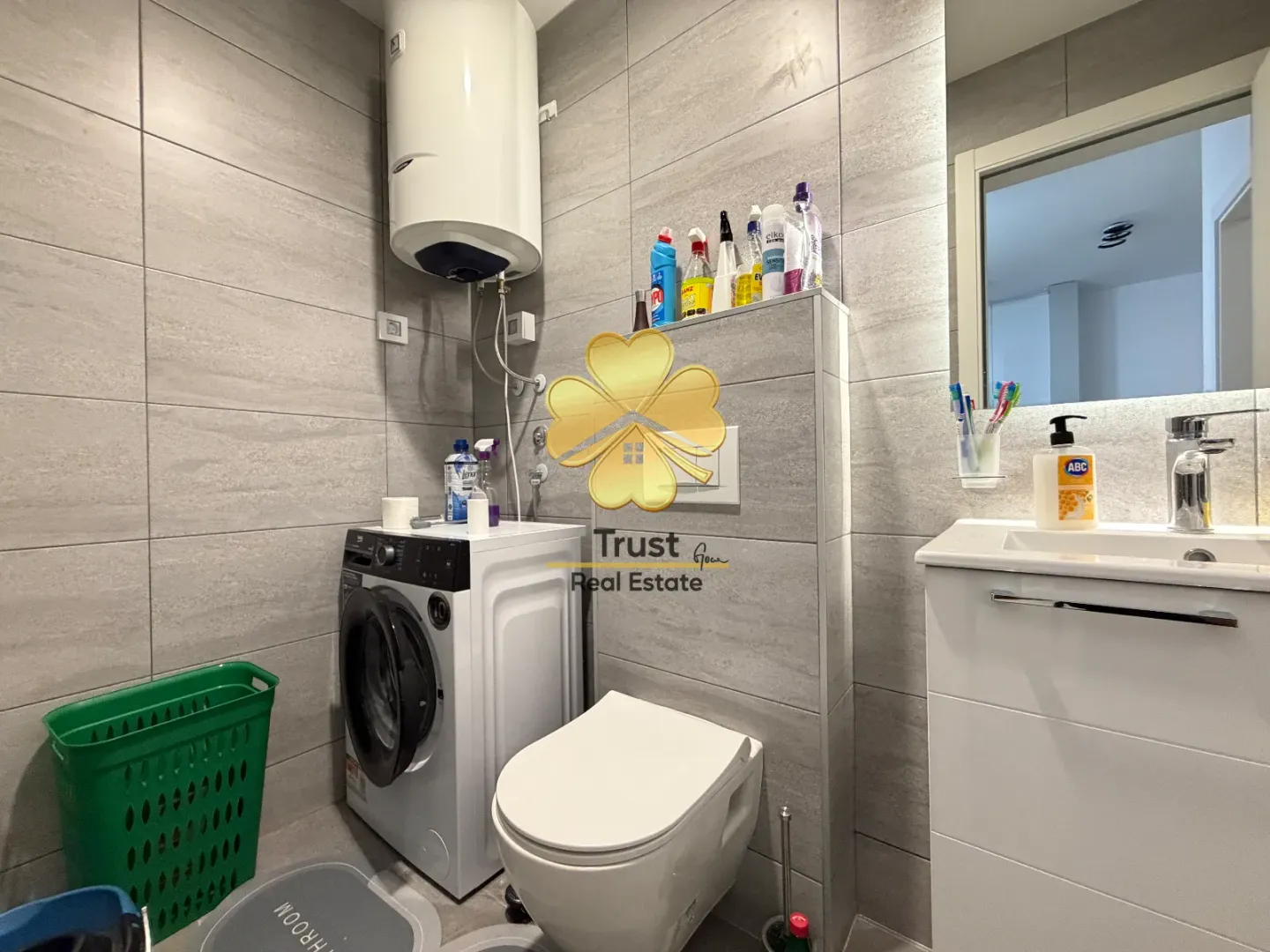 Modern bathroom with a washing machine, water heater, and sink.