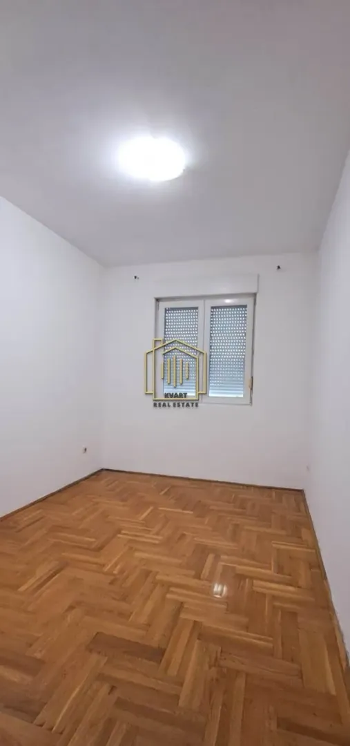 Prazna soba sa bijelim zidovima i parketom na podu.